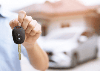 a person holding a key behind a car