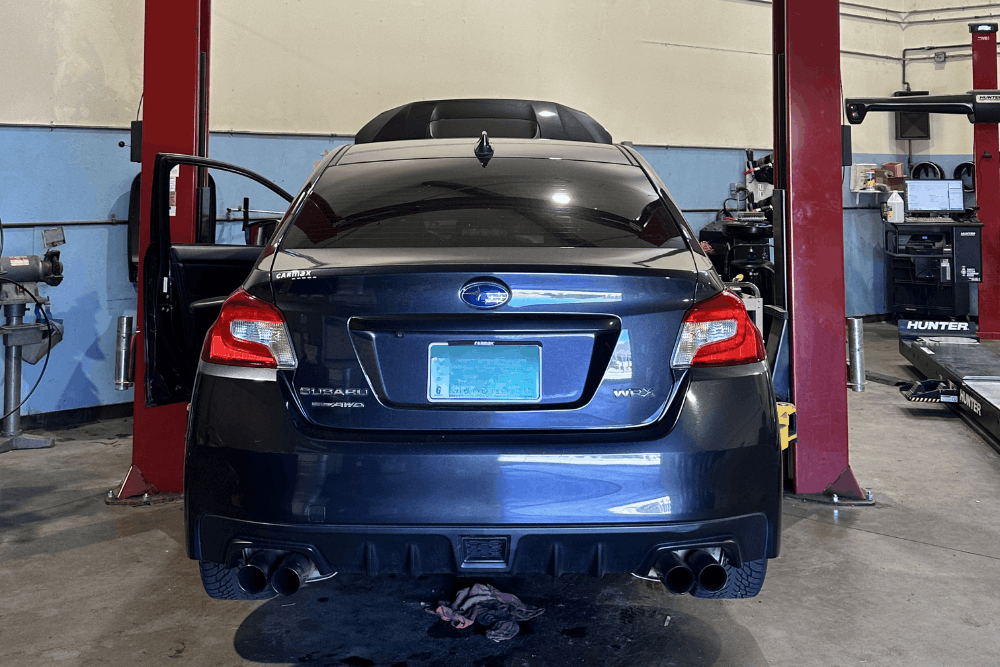 Subaru repair in Englewood, CO by Autovisions. Image of a Subaru WRX inside a professional auto repair shop, positioned on a lift bay for diagnostics, maintenance, and performance service.