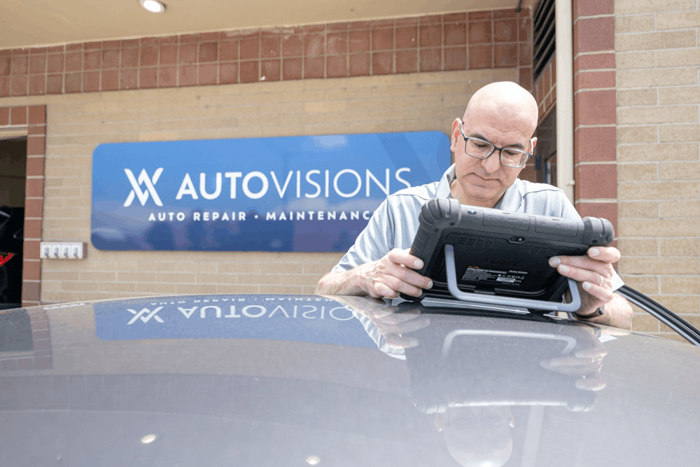 Sustainable auto repair in Englewood, CO, at Autovisions. Image of Nathan Bryant using advanced diagnostic tablet outside auto repair shop, highlighting accurate vehicle troubleshooting and modern repair technology.