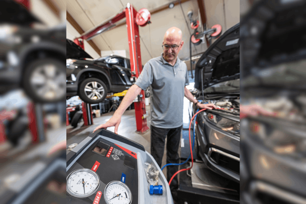 Car A/C maintenance, auto repair in Englewood, CO, at Autovisions. Image of Nathan Bryant performing an automotive A/C system recharge and diagnostic service using professional air conditioning equipment in a modern auto repair shop.