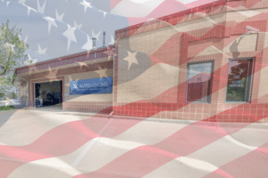 Independence Day, auto repair in Englewood, CO, at Autovisions. Exterior of AutoVisions auto repair shop in Denver, CO with an American flag overlay, highlighting trusted, locally owned automotive repair, maintenance, diagnostics, and service for domestic and import vehicles.