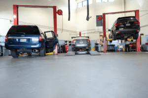Best auto repair shop, auto repair in Englewood, CO at Autovisions. Image of multiple vehicles in service bays, including SUVs raised on lifts and a technician working beneath one for maintenance.