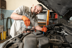 Honest mechanic, auto repair in Englewood, CO at Autovisions. Image of a technician adding fluid under an open hood while checking the engine bay to support reliable vehicle performance.