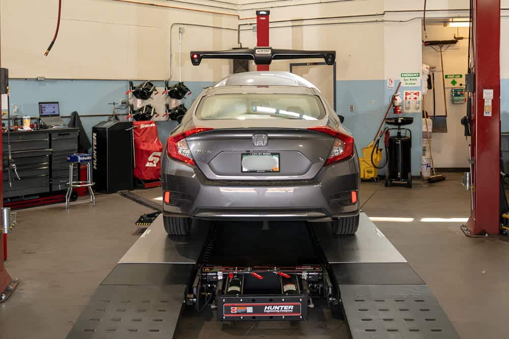 Honda repair, auto repair in Englewood, CO at Autovisions. Image of a Honda Civic positioned on a Hunter alignment rack inside the repair shop for precision wheel alignment service.
